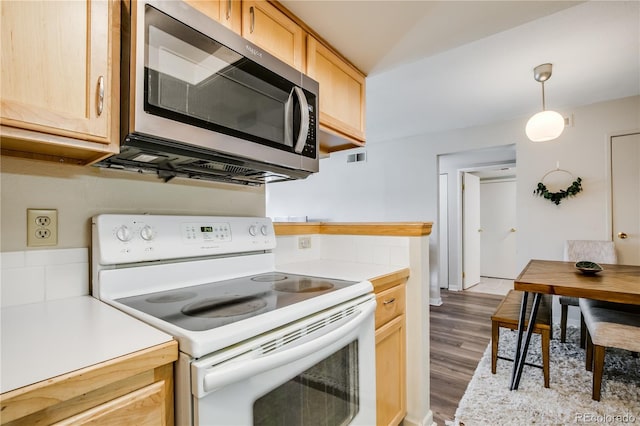 kitchen featuring light brown cabinets, white electric range, light countertops, stainless steel microwave, and decorative light fixtures