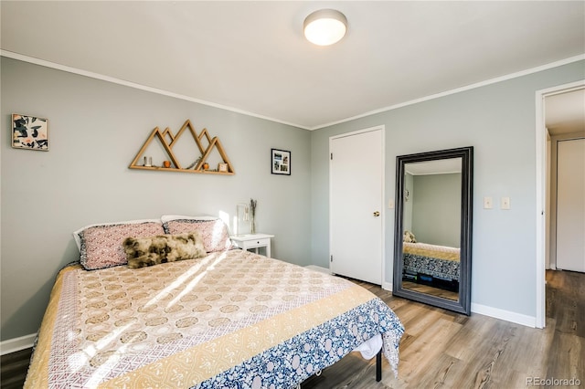 bedroom featuring baseboards, ornamental molding, and wood finished floors