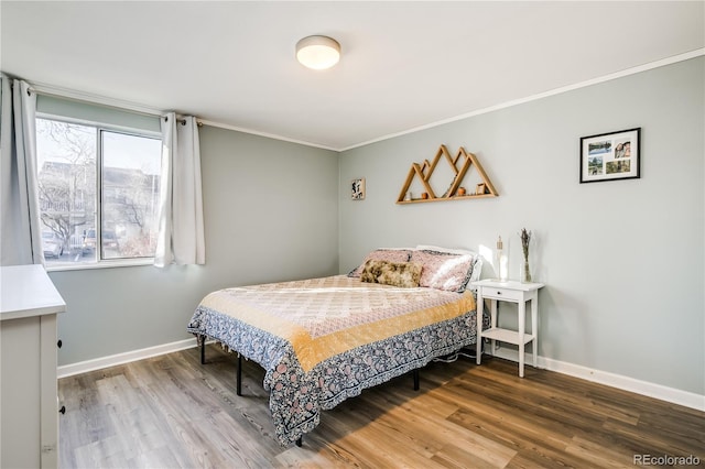 bedroom with baseboards, wood finished floors, and ornamental molding