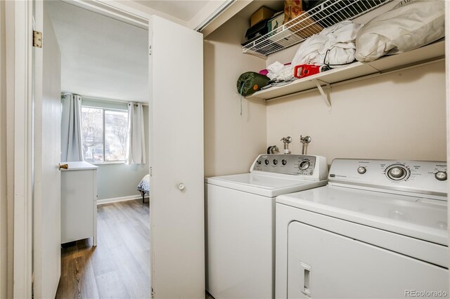 laundry room with laundry area, baseboards, separate washer and dryer, and wood finished floors