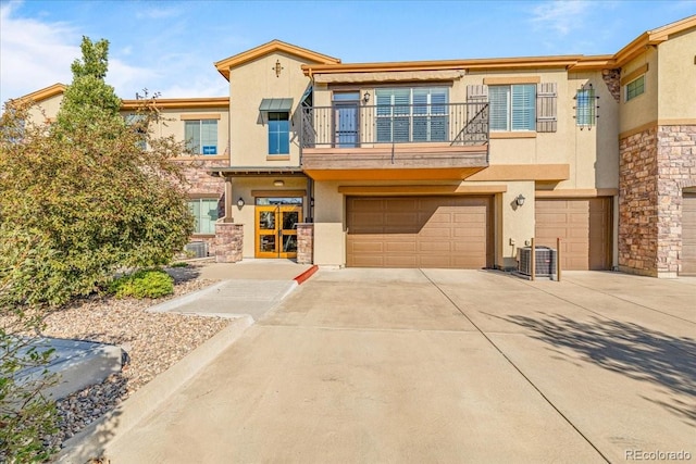 view of property with a balcony, a garage, and central AC unit