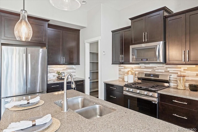 kitchen featuring decorative backsplash, dark brown cabinets, decorative light fixtures, stainless steel appliances, and light stone countertops