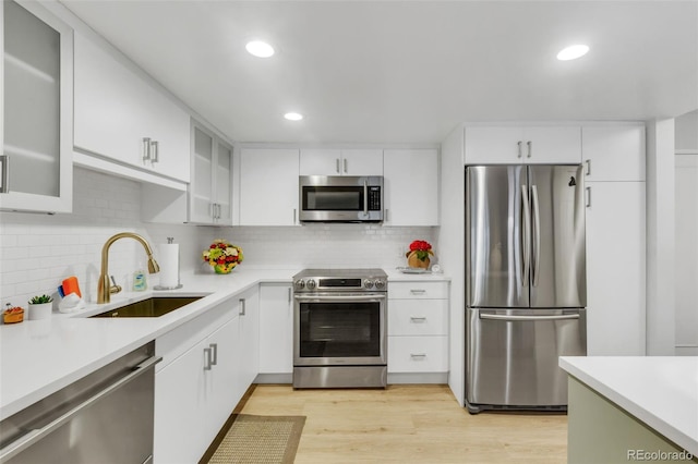 kitchen featuring light countertops, white cabinets, appliances with stainless steel finishes, and a sink