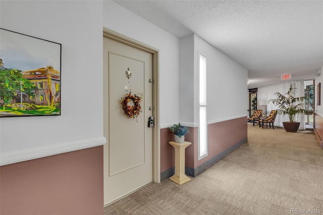 corridor with carpet flooring and a textured ceiling