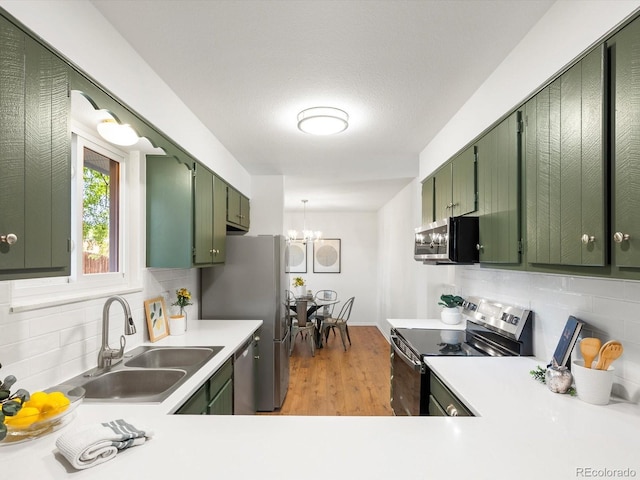 1067 E 15th Ave, Broomfield, CO 80020 - kitchen featuring green cabinetry, appliances with stainless steel finishes, decorative backsplash, and a chandelier