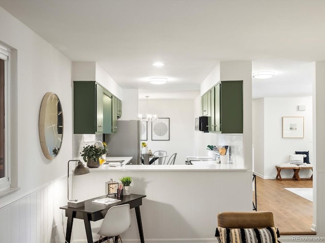 1067 E 15th Ave, Broomfield, CO 80020 - kitchen with green cabinetry, freestanding refrigerator, wood finished floors, a chandelier, and a peninsula