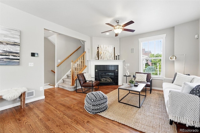 9134 E 29th Pl, Denver, CO 80238 - living room featuring stairs, wood finished floors, a ceiling fan, a tiled fireplace, and baseboards