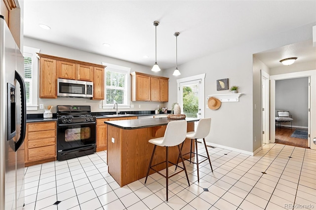9134 E 29th Pl, Denver, CO 80238 - kitchen featuring stainless steel appliances, a sink, a kitchen breakfast bar, dark countertops, and a center island