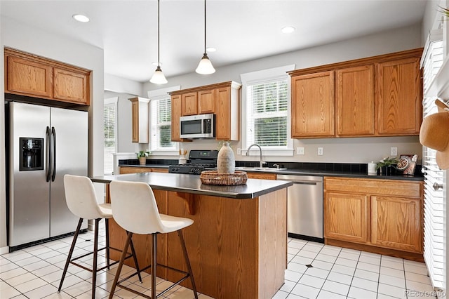 9134 E 29th Pl, Denver, CO 80238 - kitchen with stainless steel appliances, dark countertops, a center island, a kitchen bar, and decorative light fixtures