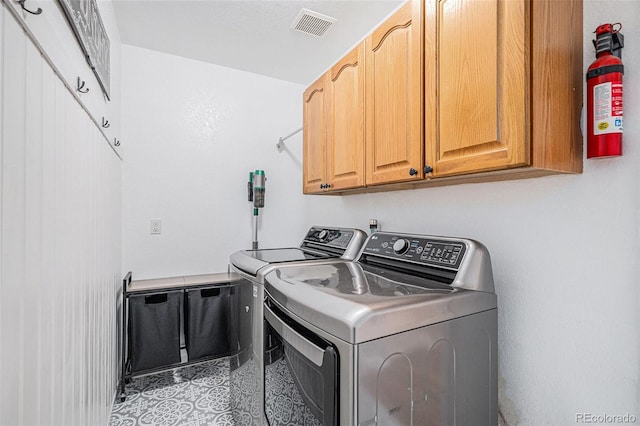 clothes washing area with washer and clothes dryer and cabinet space