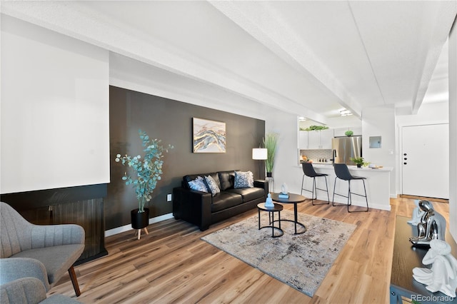 living room featuring beam ceiling and light hardwood / wood-style flooring