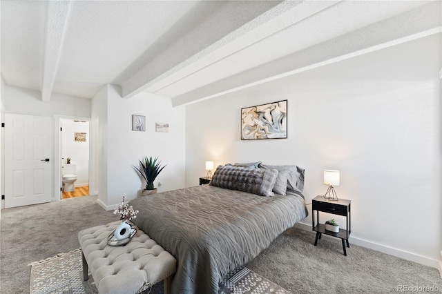 carpeted bedroom with a textured ceiling, beam ceiling, and ensuite bath