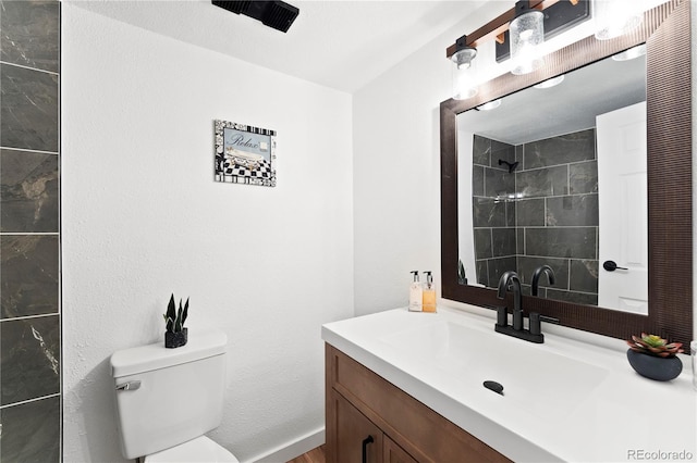 bathroom featuring vanity, toilet, and tiled shower