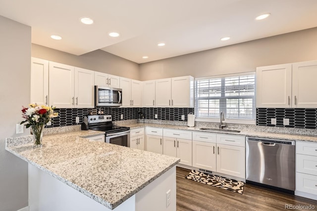 202 Ash St, Bennett, CO 80102 - kitchen with appliances with stainless steel finishes, a sink, a peninsula, white cabinets, and dark wood finished floors