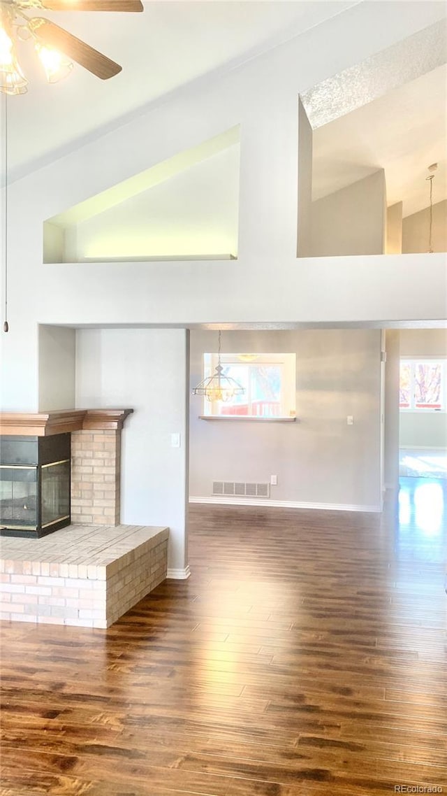 unfurnished living room featuring dark hardwood / wood-style floors, ceiling fan, and a fireplace