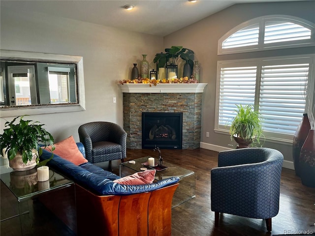 living room featuring lofted ceiling, plenty of natural light, dark wood-type flooring, and a stone fireplace