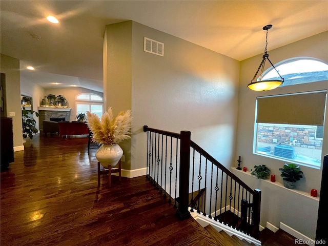 staircase with hardwood / wood-style flooring and a stone fireplace