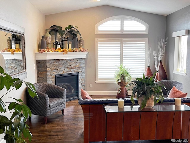 living room with a stone fireplace, dark hardwood / wood-style flooring, and vaulted ceiling