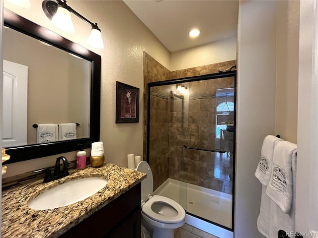 bathroom featuring vanity, a shower with shower door, and toilet