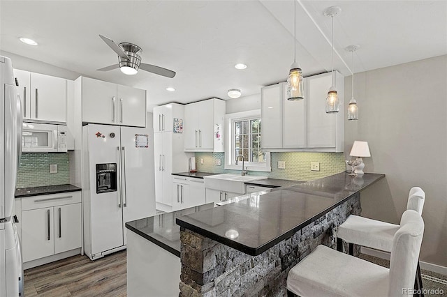 825 Hill Road Ct, Colorado Springs, CO 80909 - kitchen with white appliances, wood finished floors, a ceiling fan, a sink, and decorative backsplash