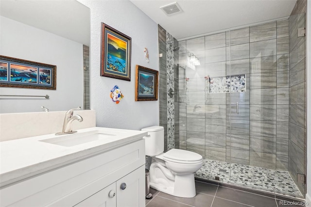 bathroom with visible vents, toilet, vanity, a stall shower, and tile patterned flooring