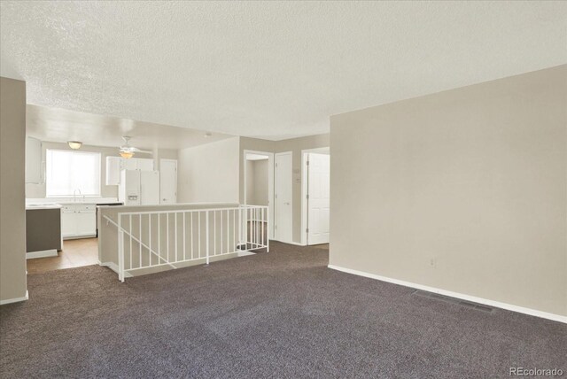 carpeted spare room with ceiling fan, a textured ceiling, and sink