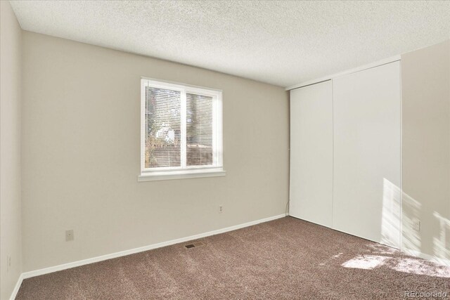 carpeted empty room with a textured ceiling