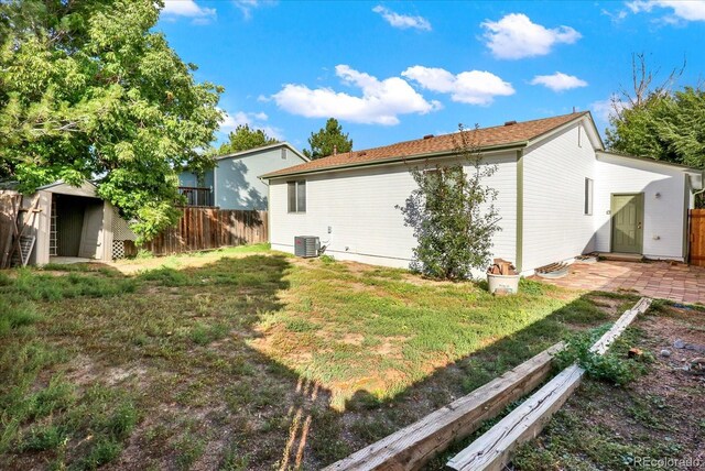 back of house featuring a lawn, a shed, and central air condition unit