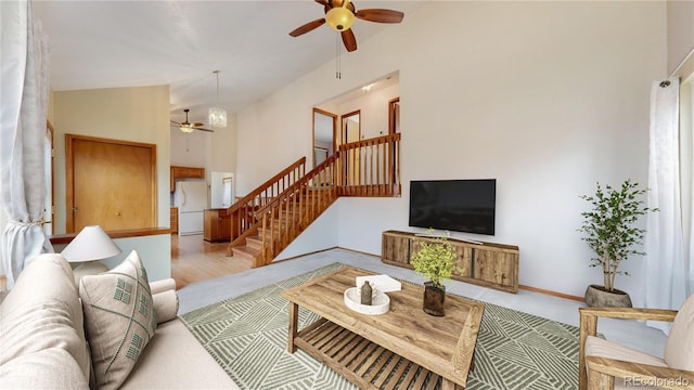 living area featuring a ceiling fan, stairs, and baseboards