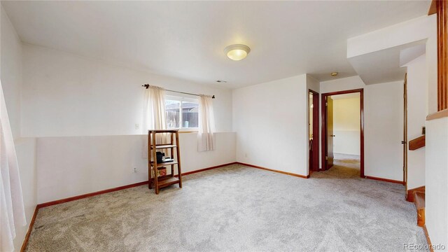 carpeted spare room featuring baseboards
