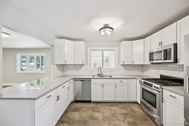 4560 S Fox St, Englewood, CO 80110 - kitchen with stainless steel appliances, a peninsula, decorative backsplash, light countertops, and white cabinets