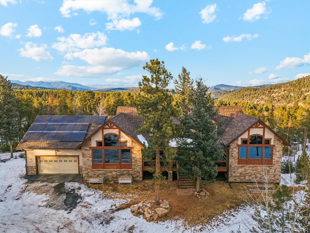 view of front facade featuring a garage, a mountain view, and solar panels