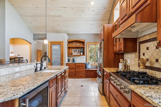 kitchen with pendant lighting, sink, stainless steel appliances, wine cooler, and light stone counters