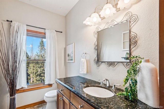 bathroom with vanity, a healthy amount of sunlight, an inviting chandelier, and toilet