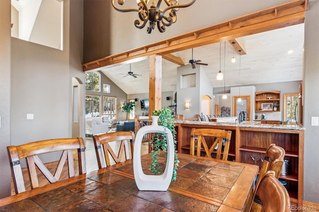 dining area featuring beamed ceiling, ceiling fan with notable chandelier, and high vaulted ceiling