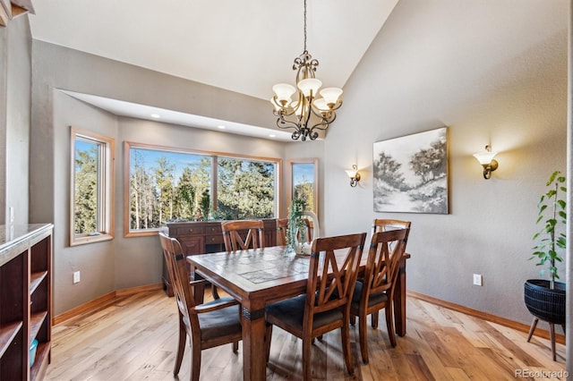 dining area featuring vaulted ceiling, a notable chandelier, and light wood-type flooring