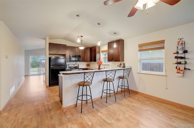 kitchen featuring visible vents, a kitchen bar, vaulted ceiling, a peninsula, and black appliances