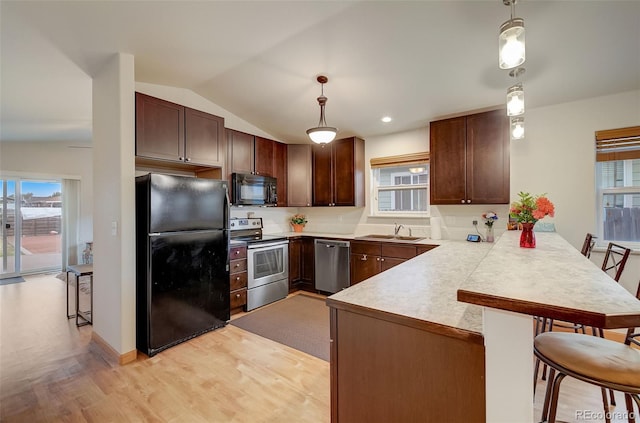 kitchen featuring a breakfast bar, light countertops, a peninsula, black appliances, and a sink