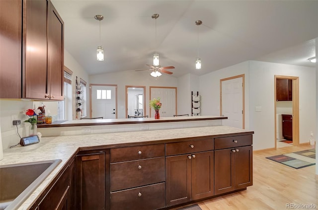 kitchen with light wood-type flooring, pendant lighting, a sink, a peninsula, and light countertops