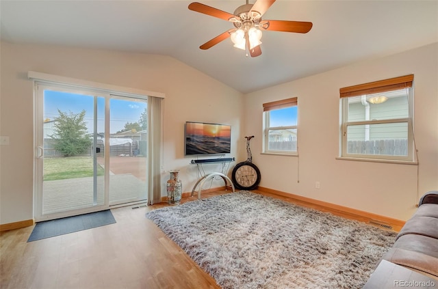 living area with vaulted ceiling, wood finished floors, baseboards, and ceiling fan