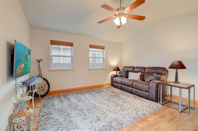 living room with ceiling fan, baseboards, lofted ceiling, and wood finished floors