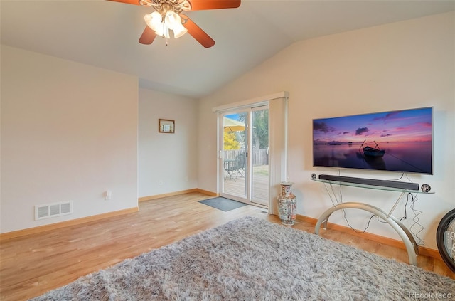 living room featuring visible vents, baseboards, lofted ceiling, and wood finished floors