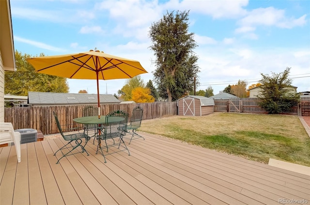 wooden deck with a storage shed, a fenced backyard, outdoor dining area, an outbuilding, and a yard