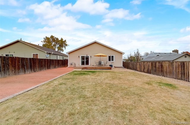 back of house featuring a yard, a wooden deck, and a fenced backyard