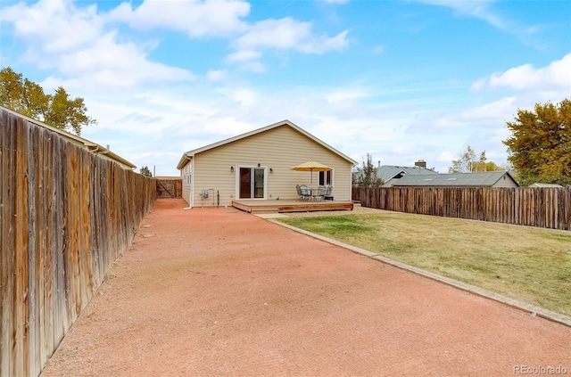 rear view of house featuring a lawn, a wooden deck, and a fenced backyard