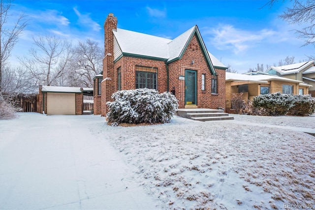 view of snowy exterior with a chimney and brick siding