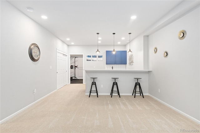 kitchen featuring blue cabinets, hanging light fixtures, light carpet, a kitchen breakfast bar, and kitchen peninsula