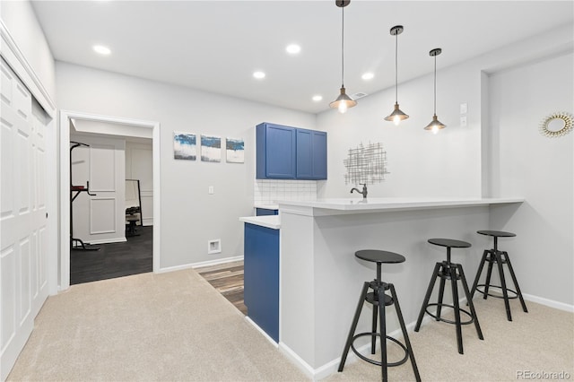 kitchen with hanging light fixtures, a breakfast bar, kitchen peninsula, and blue cabinets