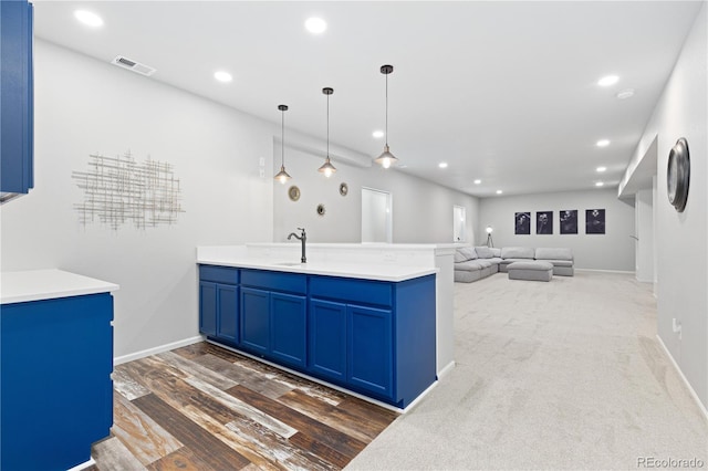 kitchen with sink, blue cabinetry, pendant lighting, and dark wood-type flooring