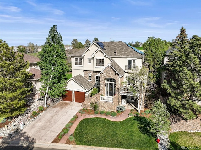 view of front of property featuring stucco siding, stone siding, driveway, roof mounted solar panels, and a front yard